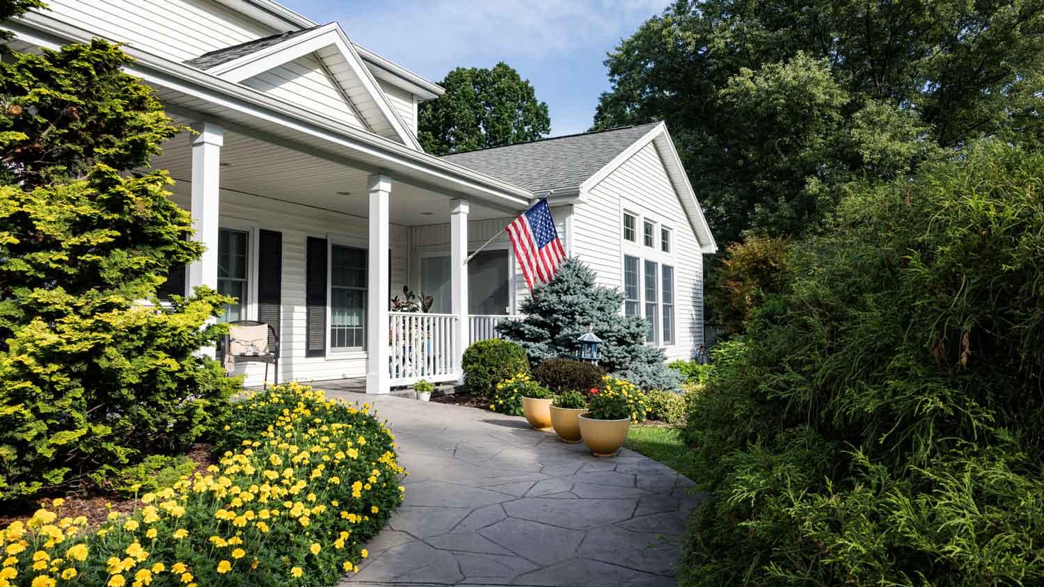 A suburban house with a concrete front walkway and a flower bed