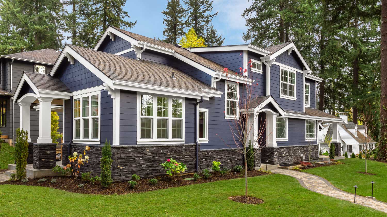 Home exterior with green lawn and forest in background