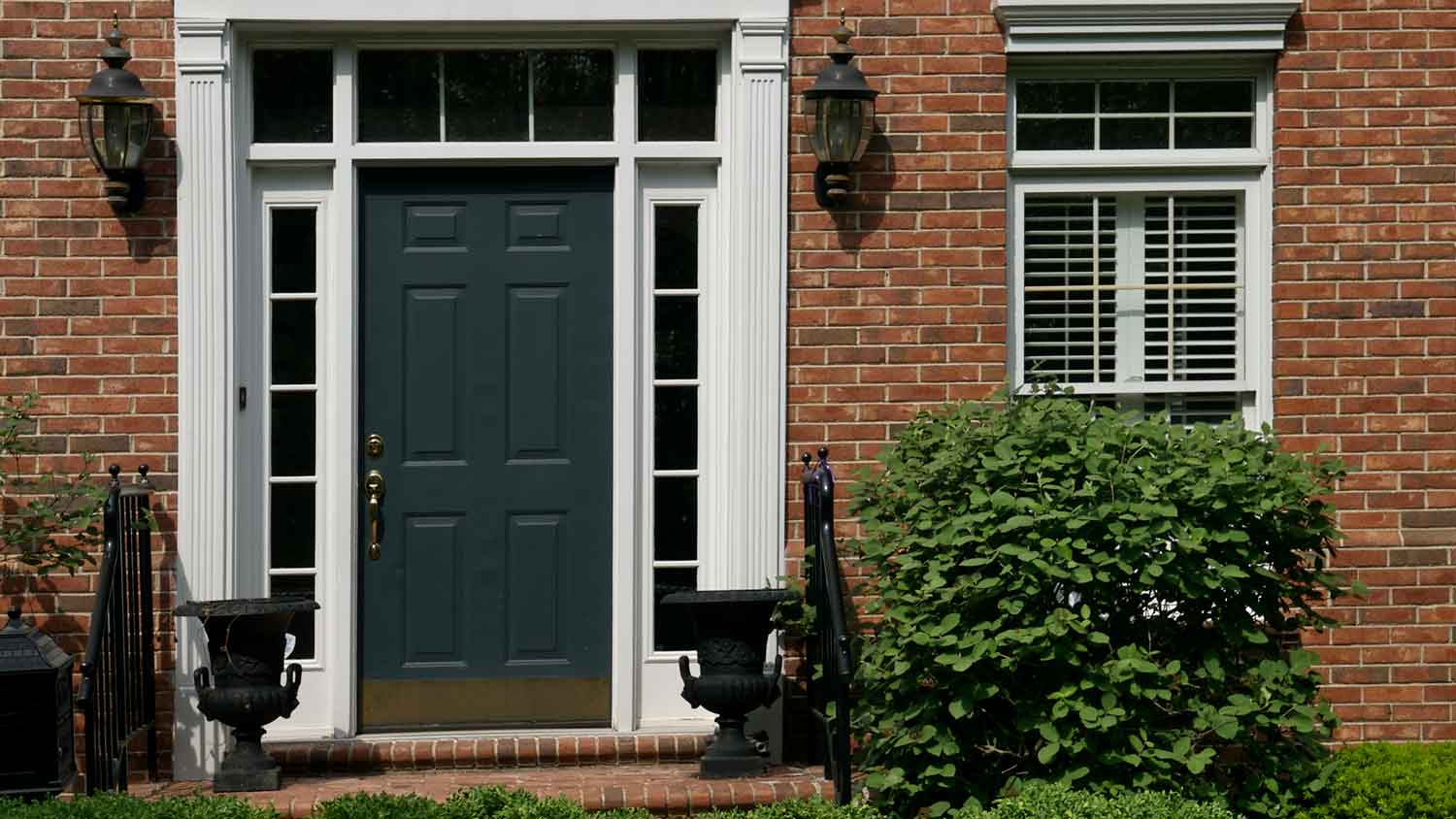 A dark gray front door on a red brick house