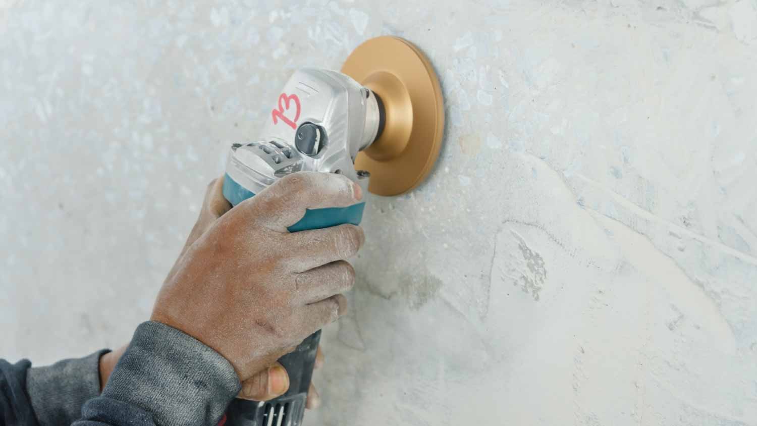 Construction worker grinding the concrete wall