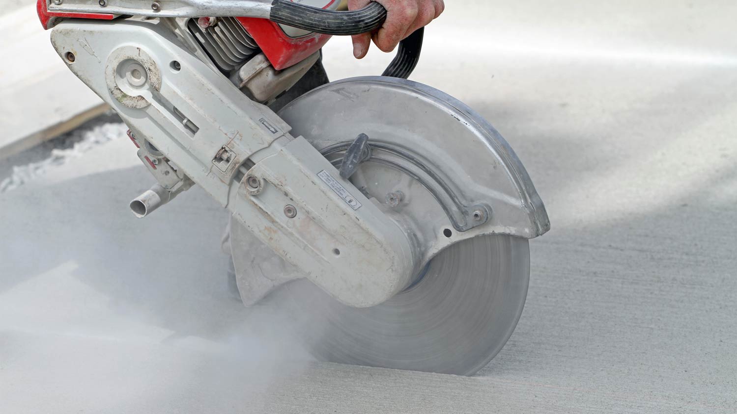 man using cut off saw on sidewalk