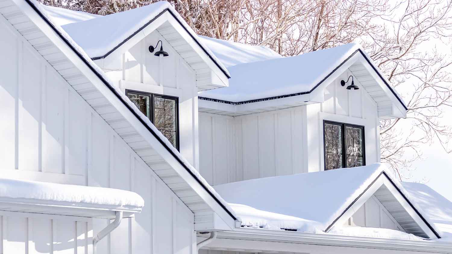 Home with board and batten siding covered with snow