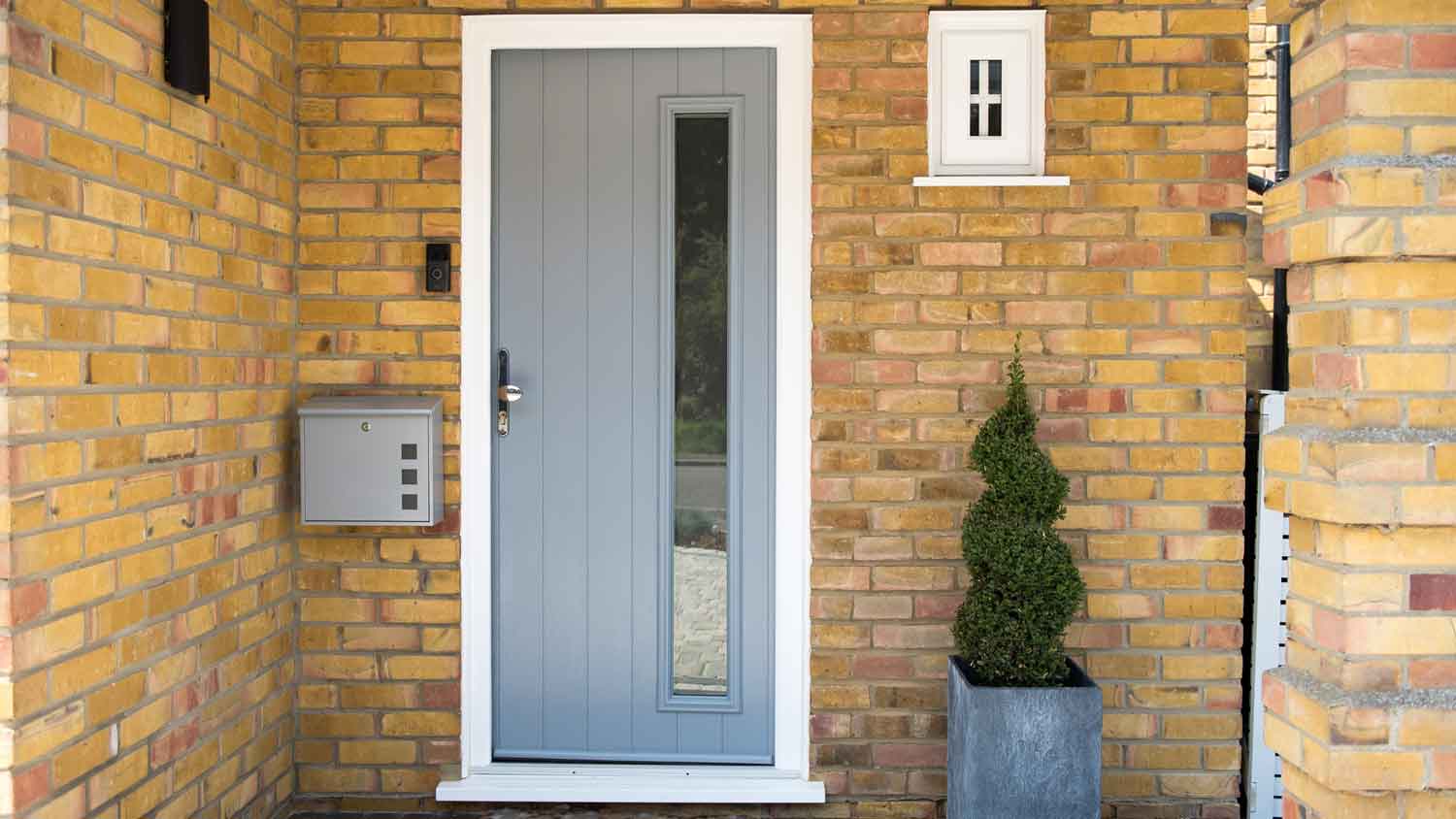 A light gray front door in a brick house