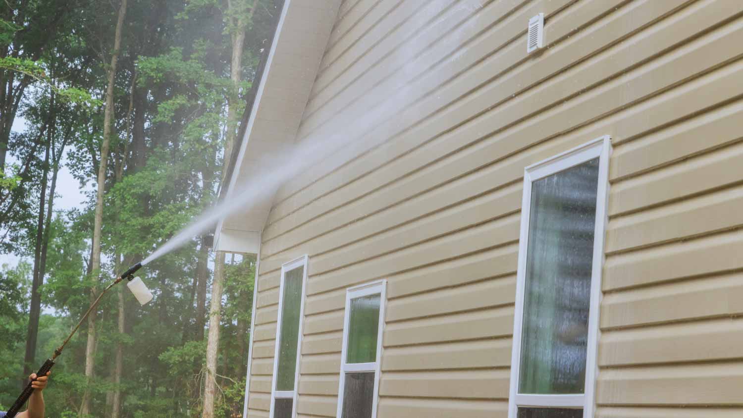 A person power washing his house