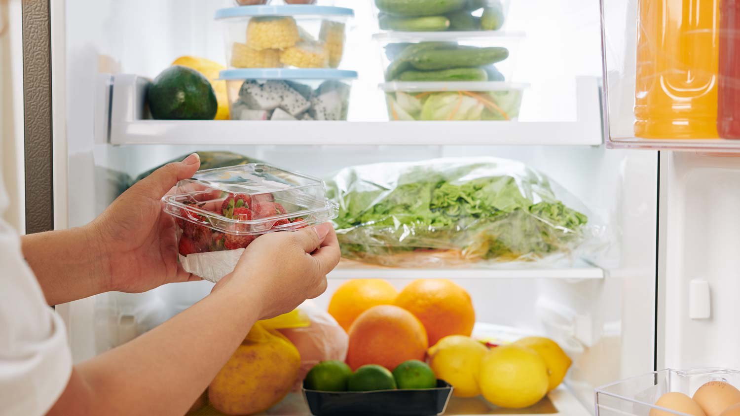 A person placing fruit in a fridge