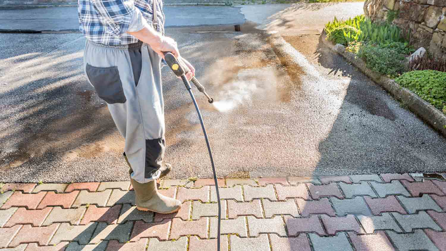 man using pressure washing to clean entrance