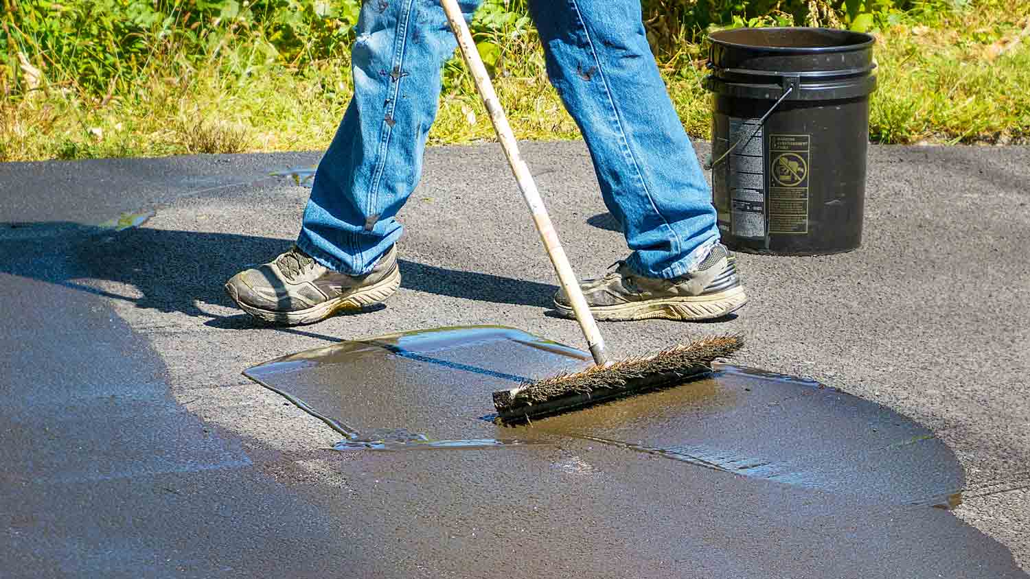 man resealing asphalt driveway
