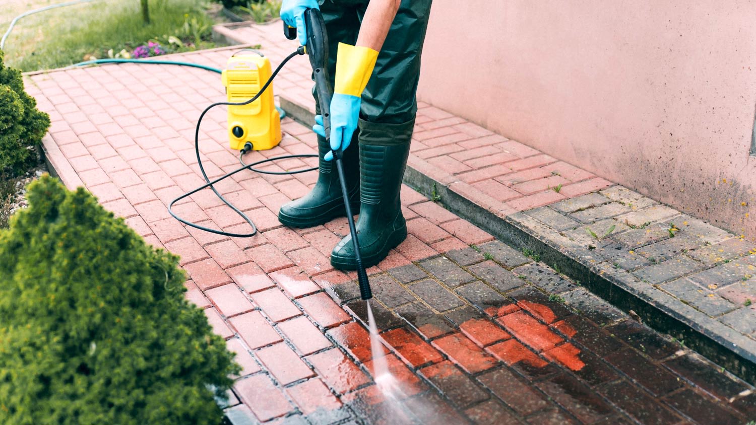 Man cleaning brick with pressure cleaner