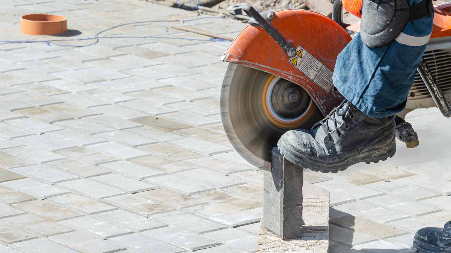 Worker cutting paver with circular saw