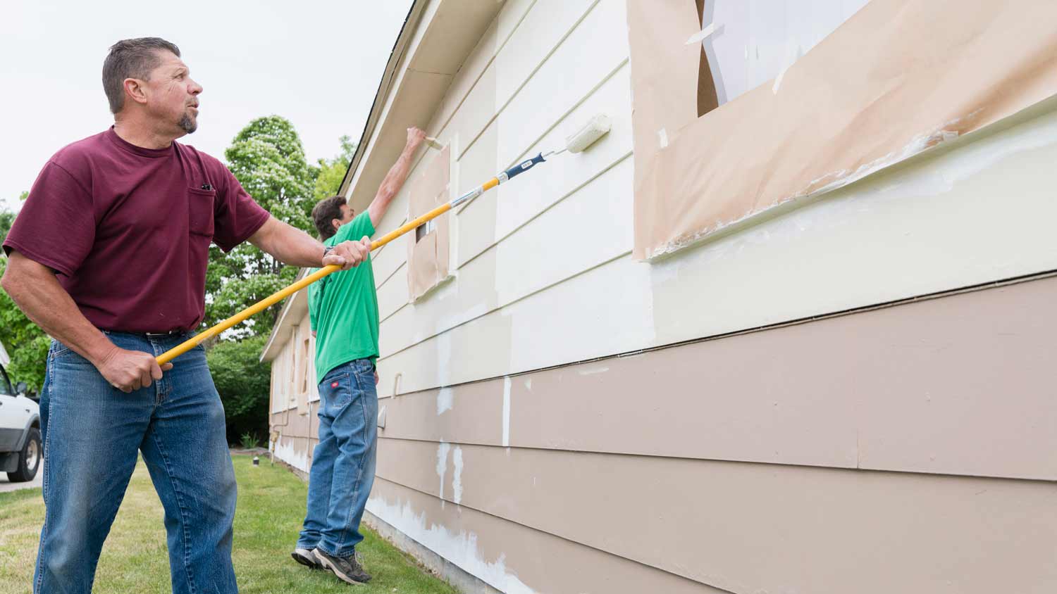 2 men paint vinyl siding with brush roller