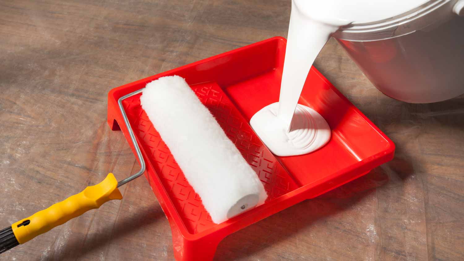 Pouring a white latex paint in a paint tray
