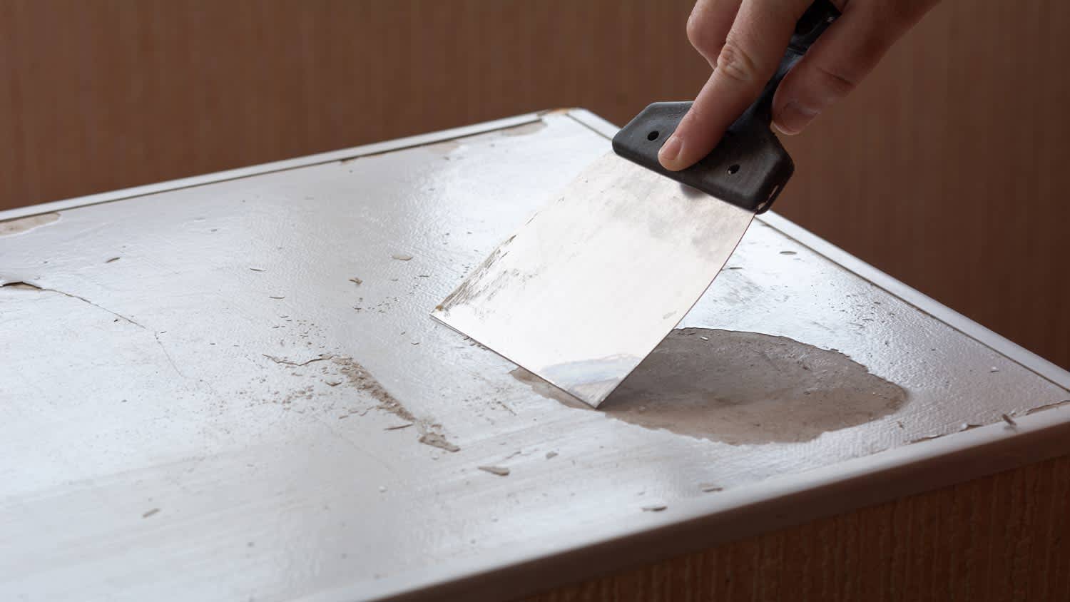 person scraping off paint on metal surface