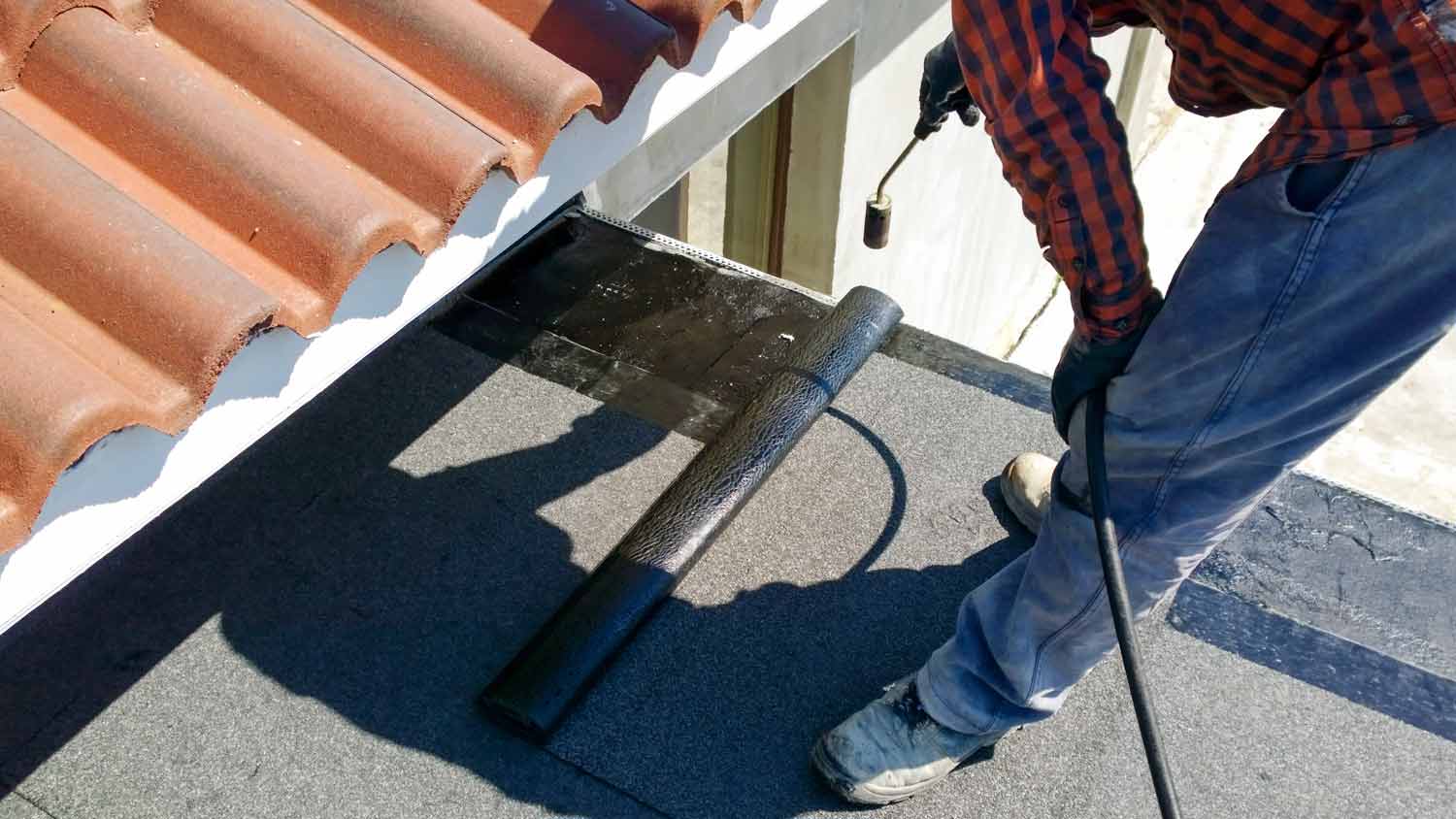roofer applying bitumen to roof