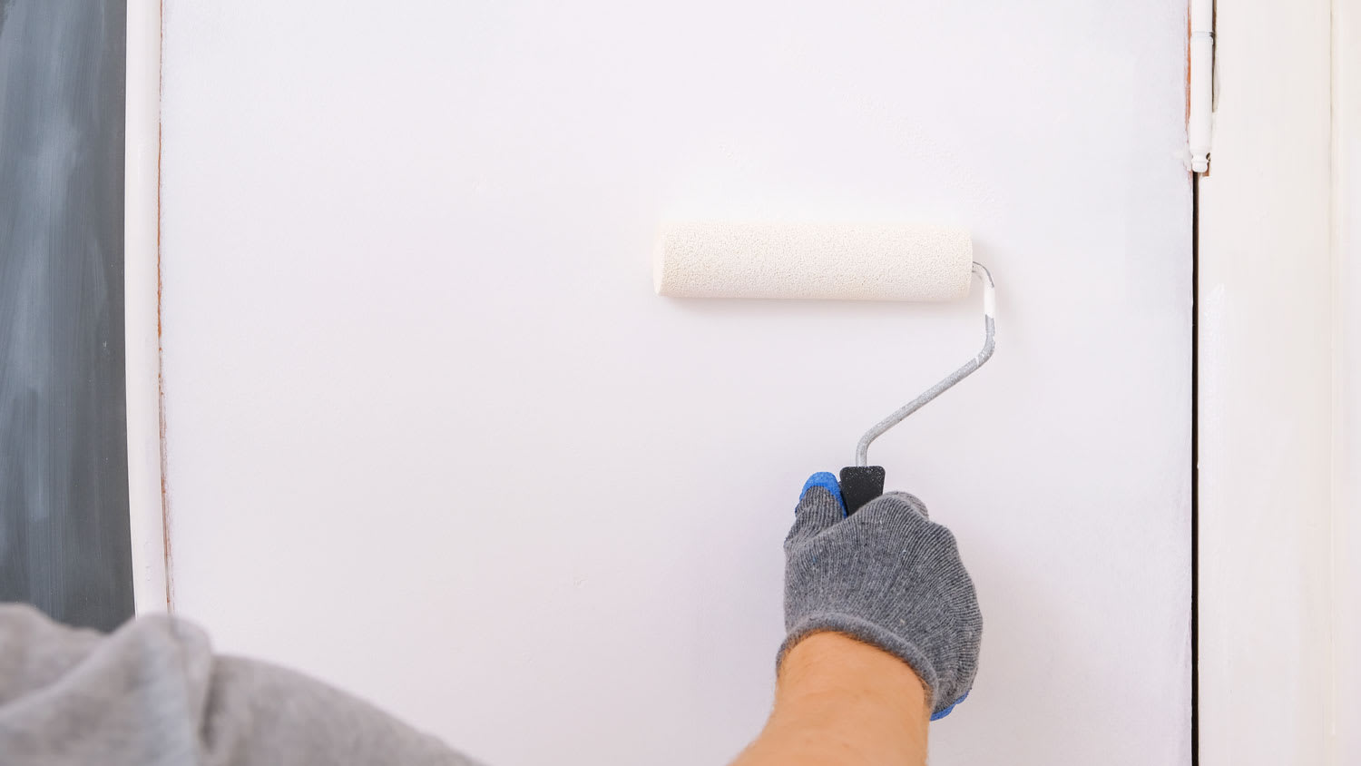 A person painting with a roller a metal door