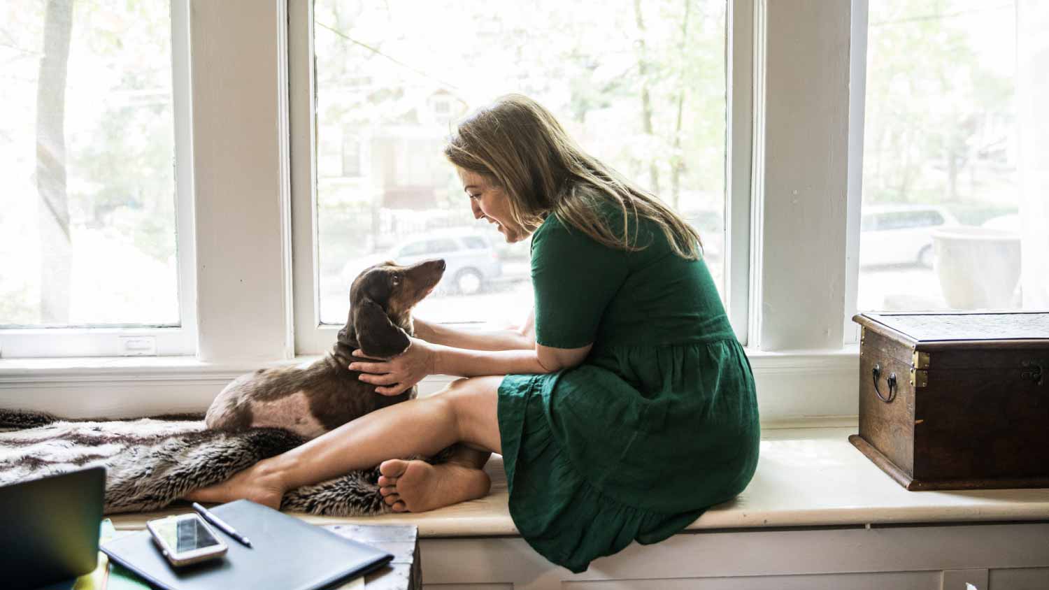 Woman sitting next to the window with her dog