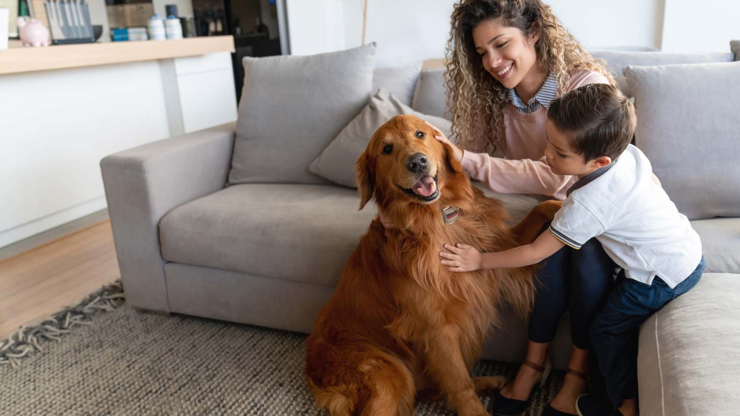 A mother and her son petting their dog in the living room