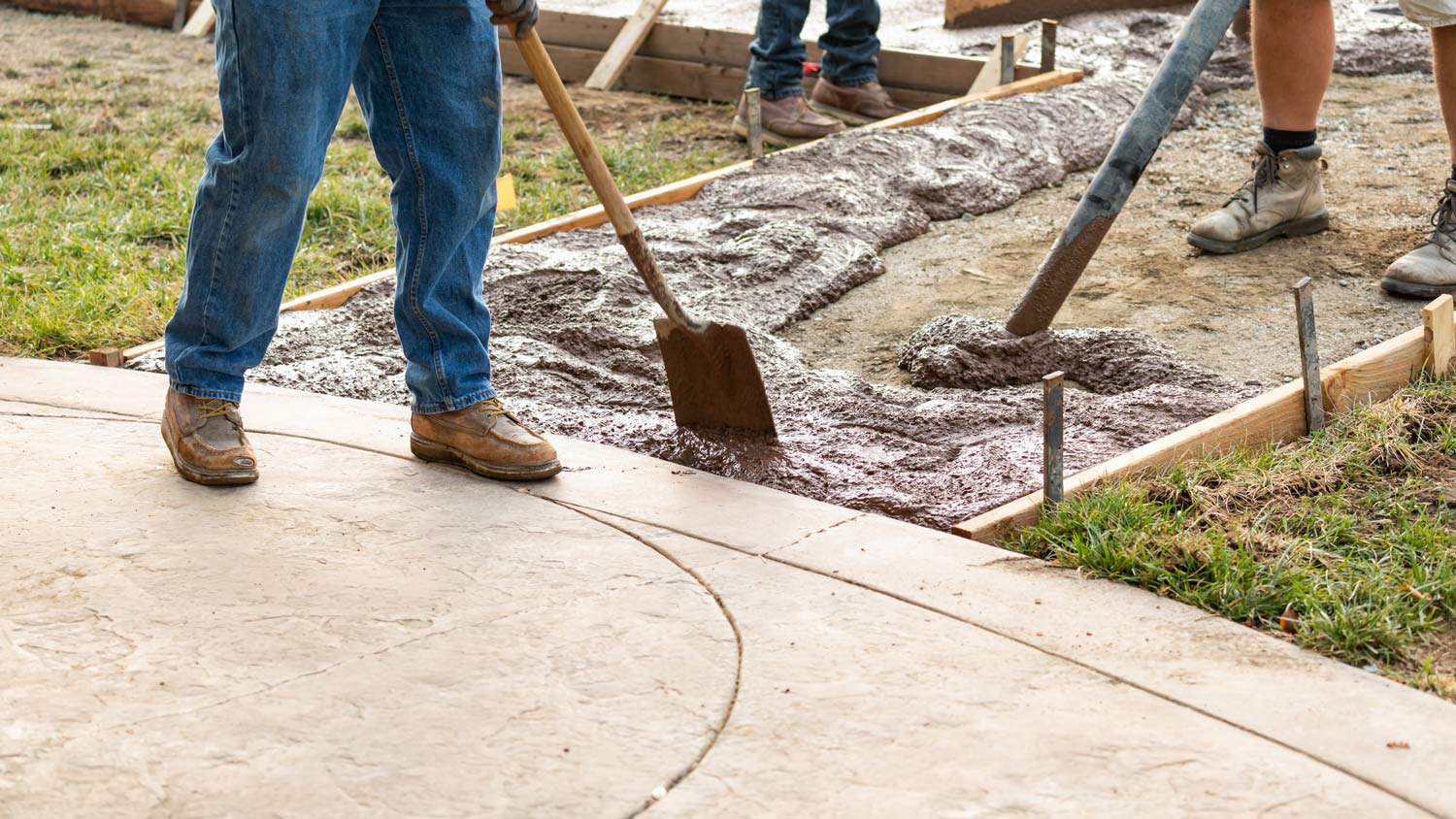 Construction Worker Pouring Wet Deck Cement Into Wooden Frame