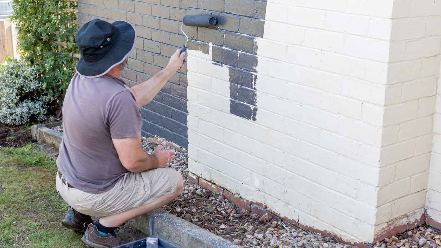 man paint house exterior with brush roller