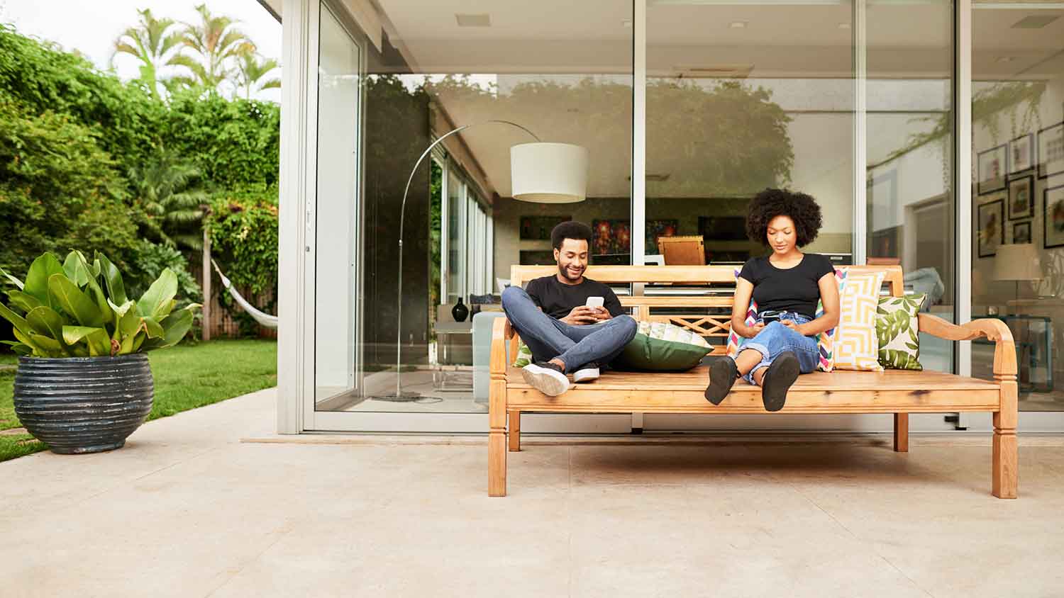Couple sitting on a couch on the patio using their phones