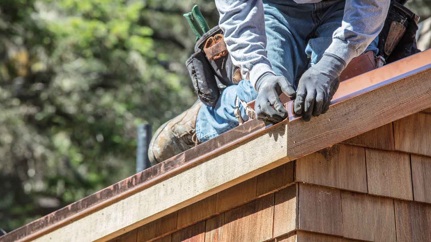 Worker installing coper flashing on the roof