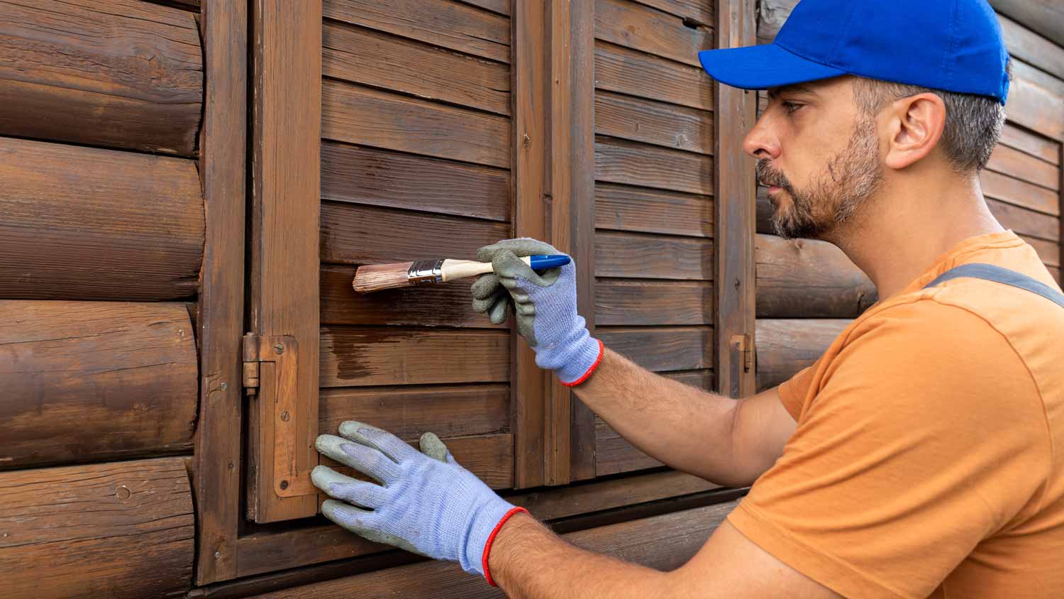 A man painting with a brush wooden shutters