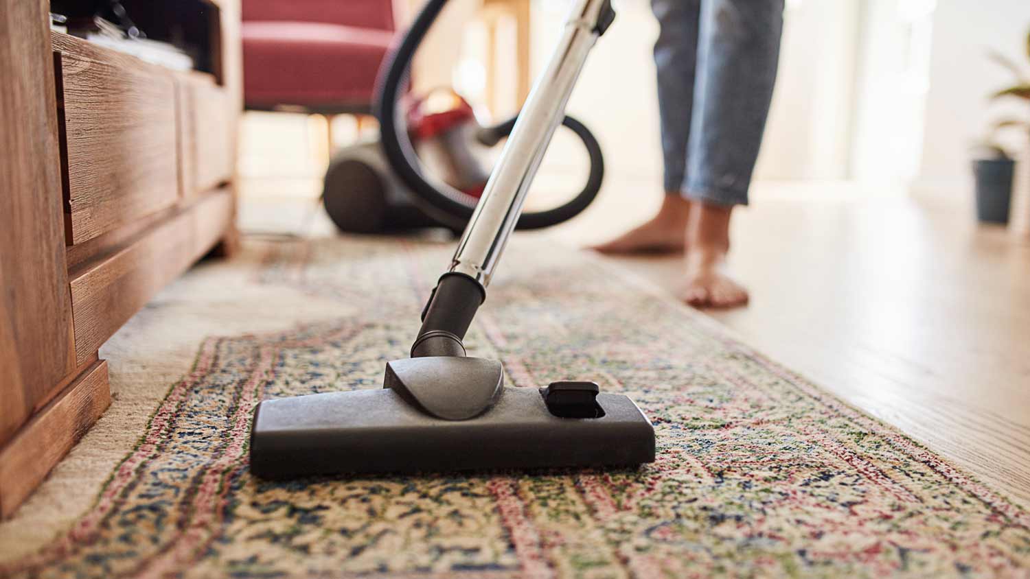 woman vacuuming area rug in living room