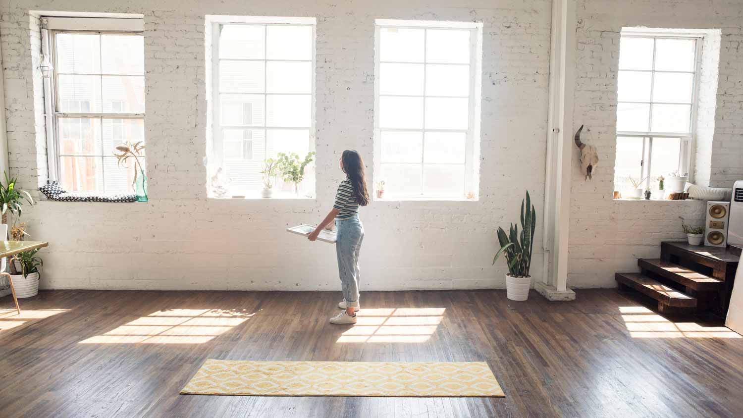 A woman hanging a frame on a limewashed wall