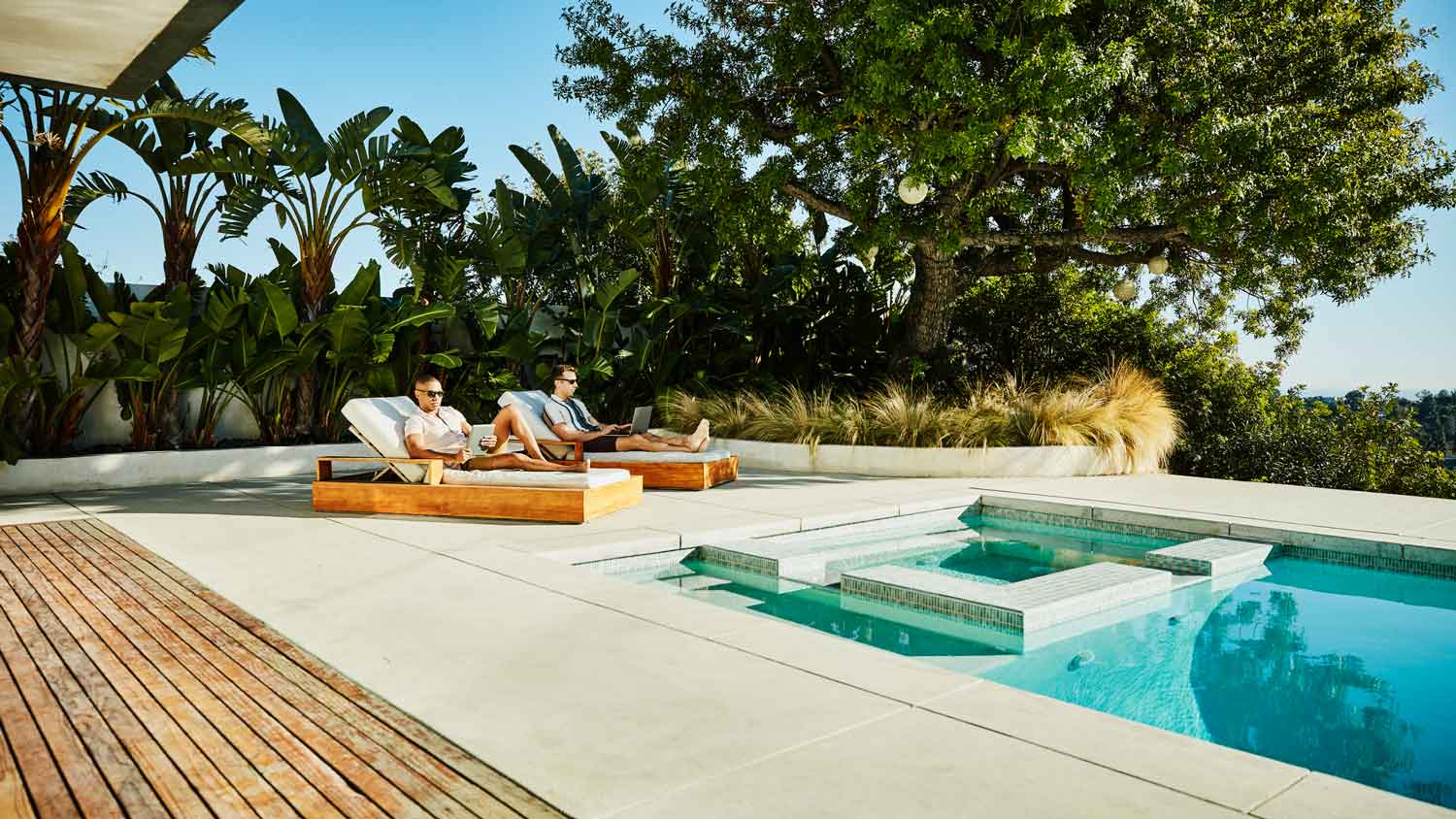 A couple relaxing on lounge chairs on the deck by the pool