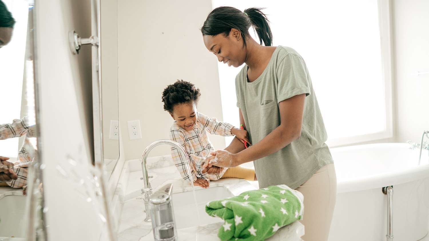 Mom washes hands with toddler in the bathroom