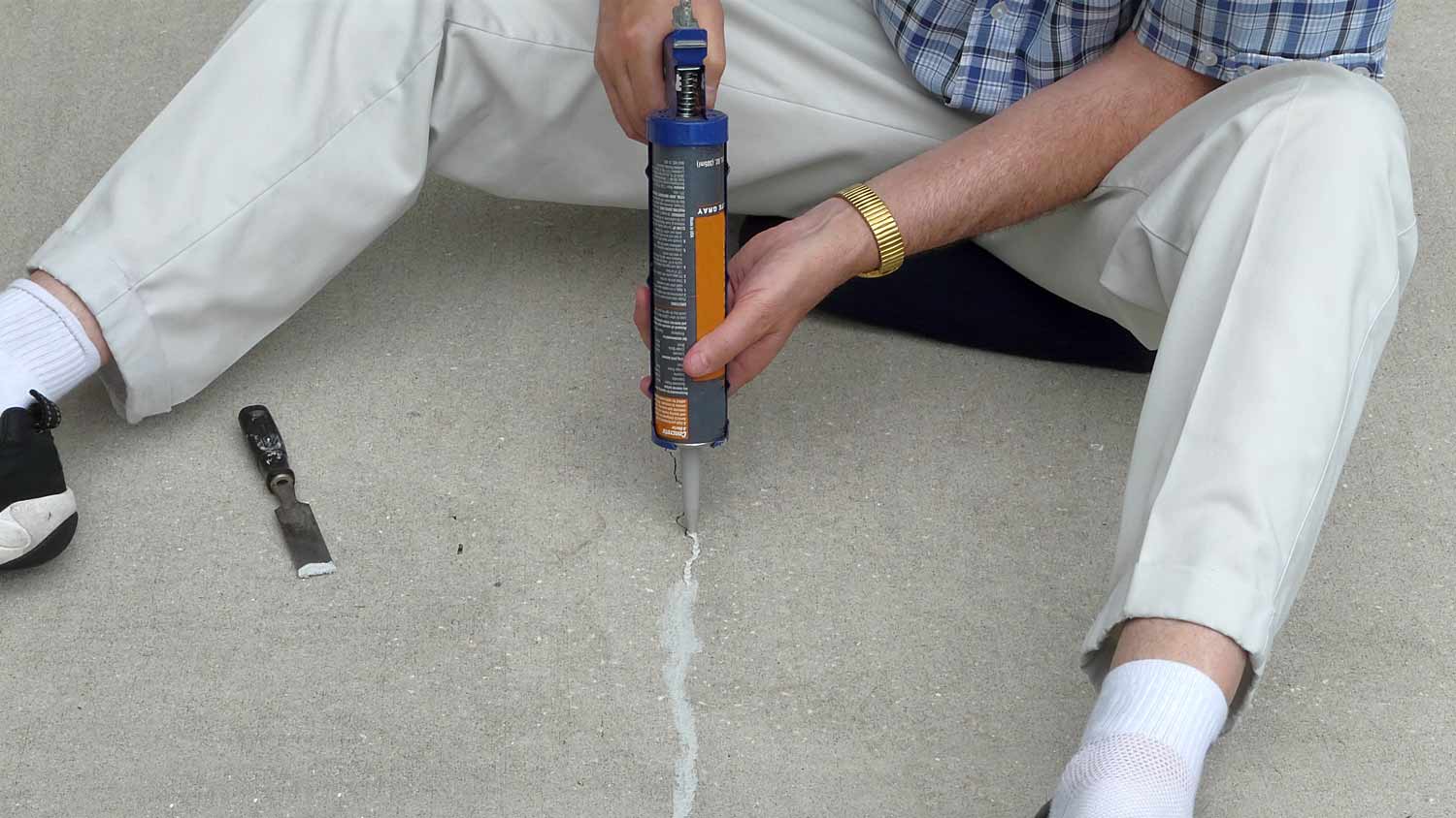 man using water sealant on crack in concrete