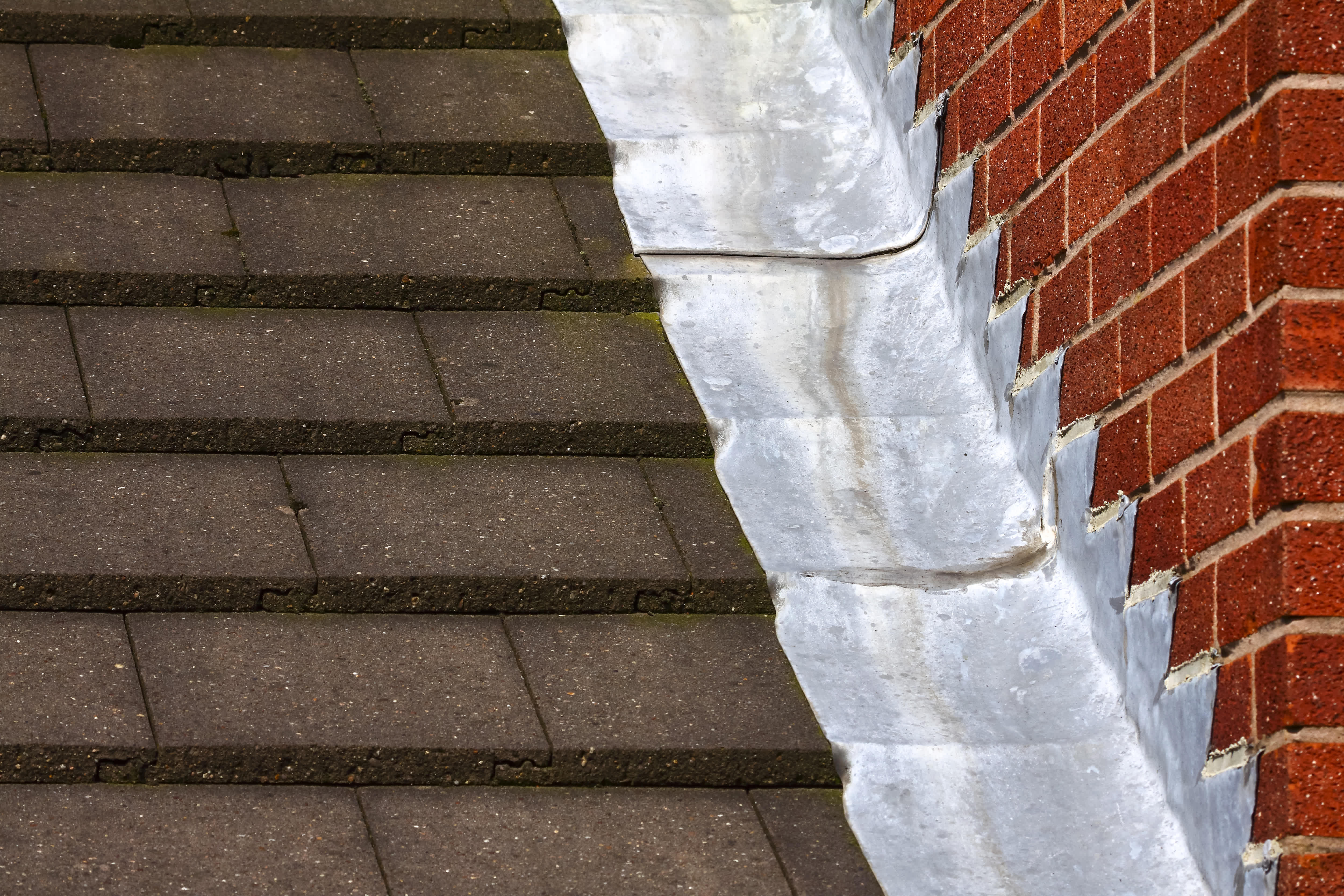 A roof with step flashing going up a brick wall