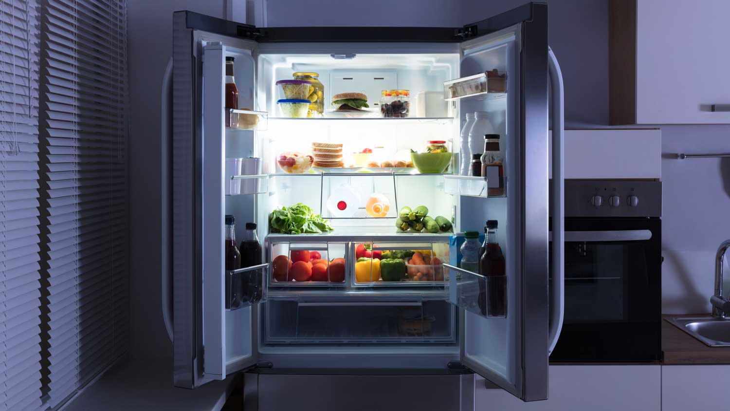 An open double refrigerator filled with vegetables and fruit
