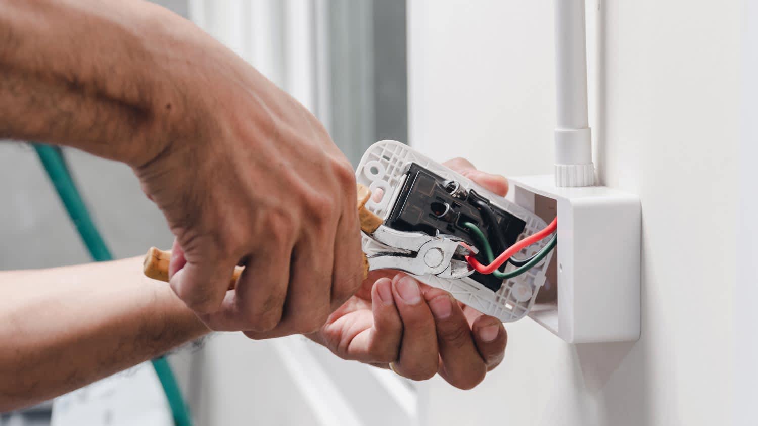 man using pliers to install power outlet