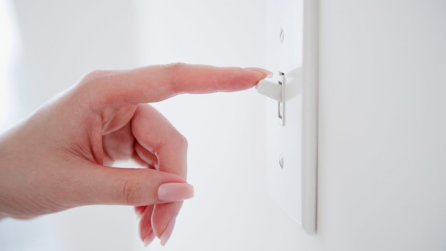 A hand turning on a light switch