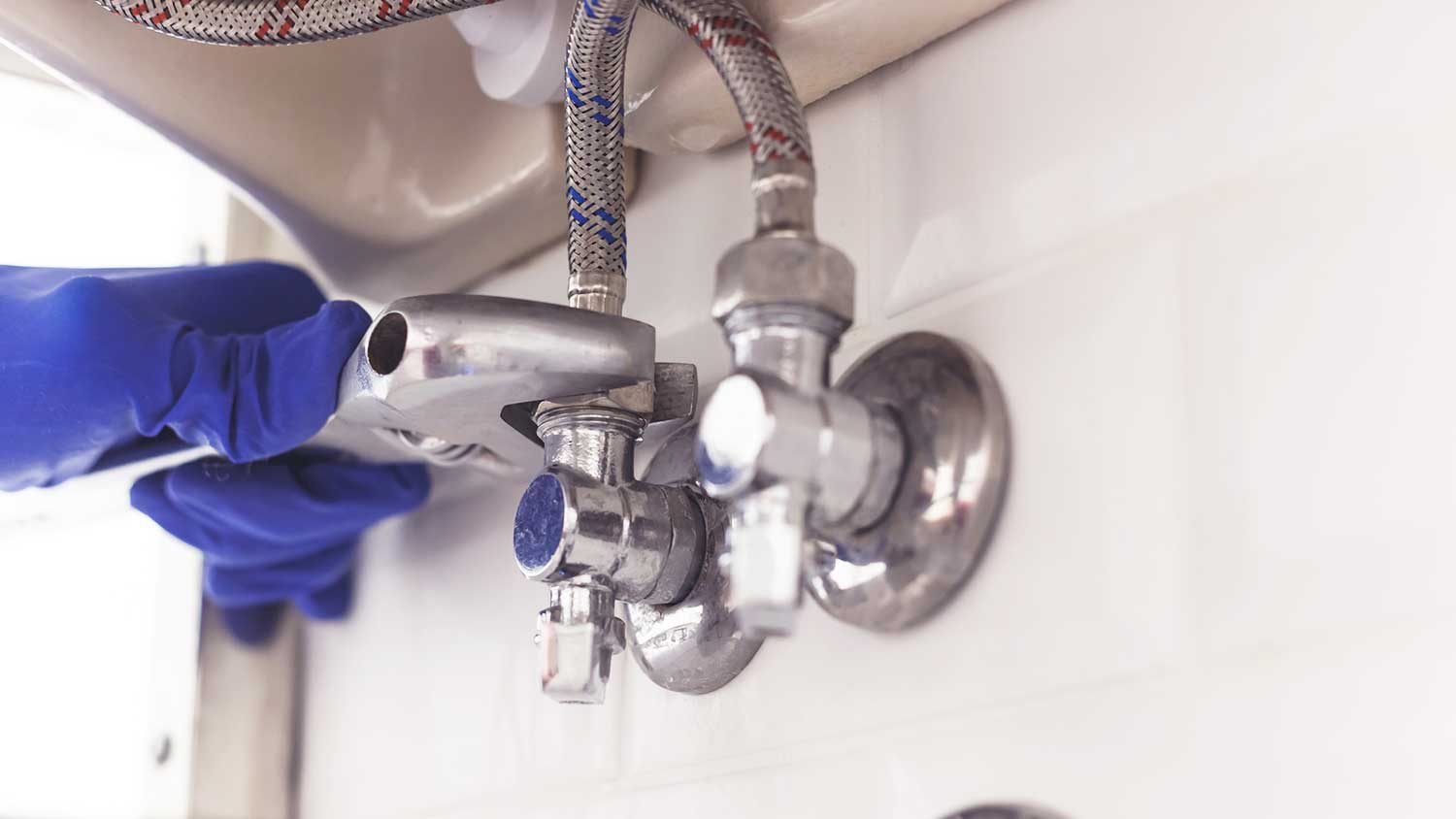 Plumber installing water supply lines under the sink