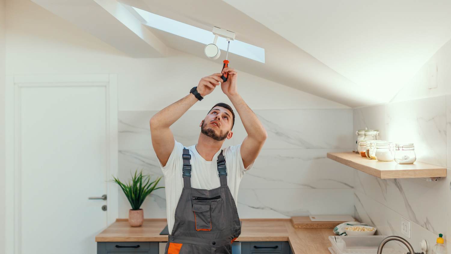 Man working on light socket in kitchen