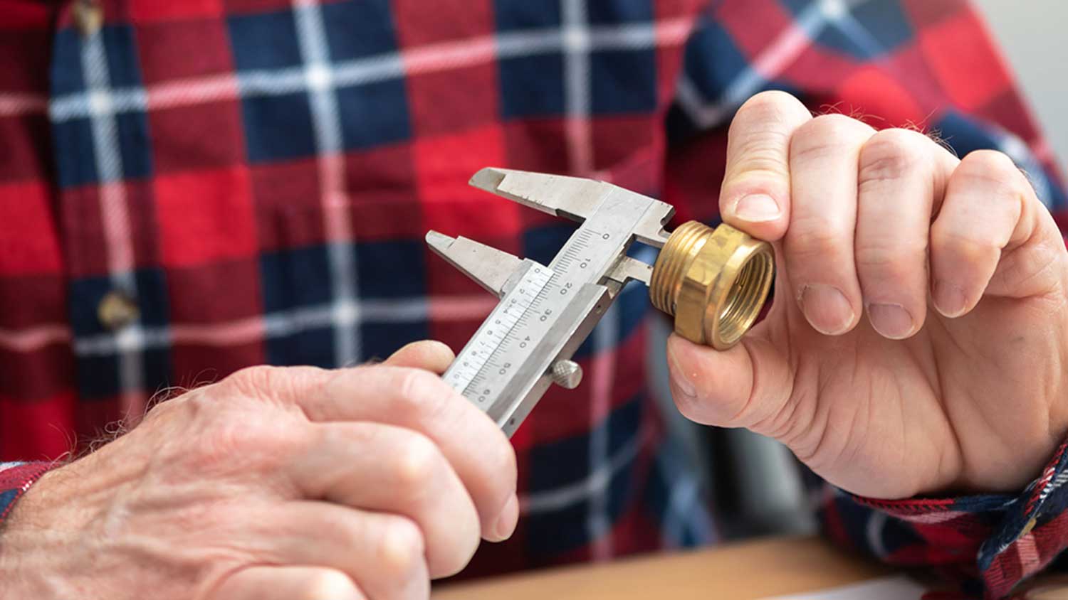 Plumber using a caliper to measure a female pipe