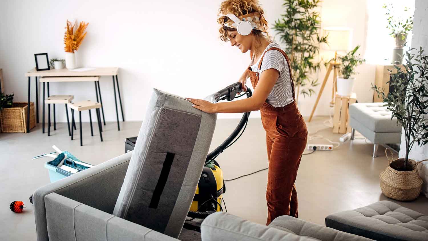 Woman cleaning sofa with a steam cleaner