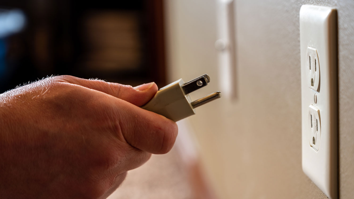 man gripping a power plug to put into outlet