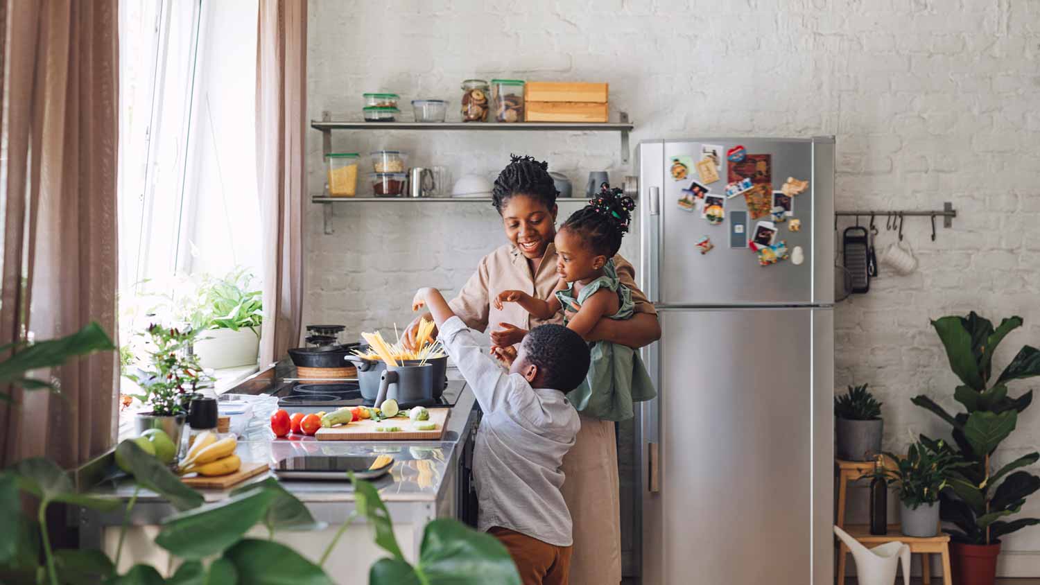 A mother with her son and daughter cooking spaghetti in the kitchen