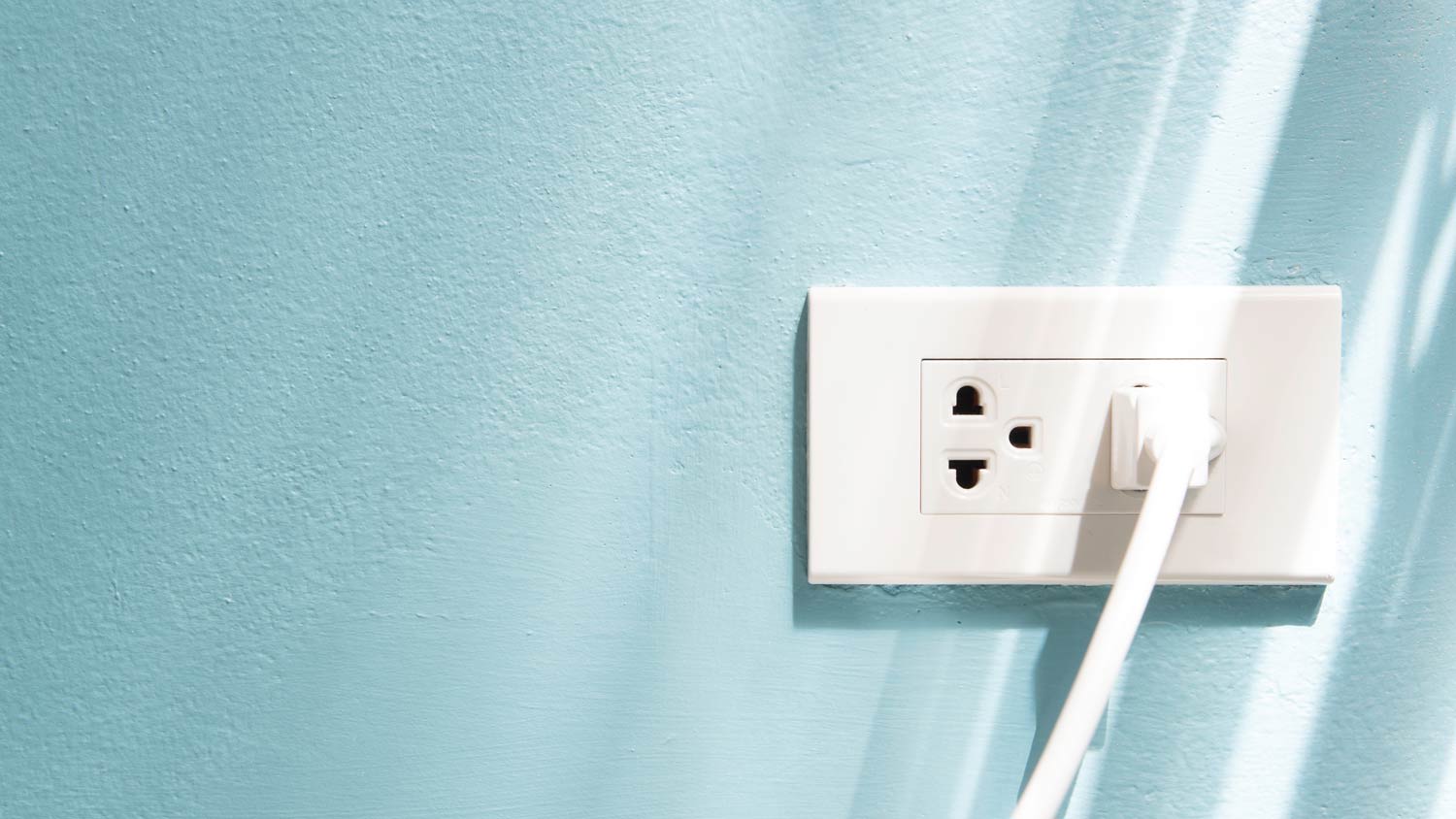 blue wall with white plug in outlet