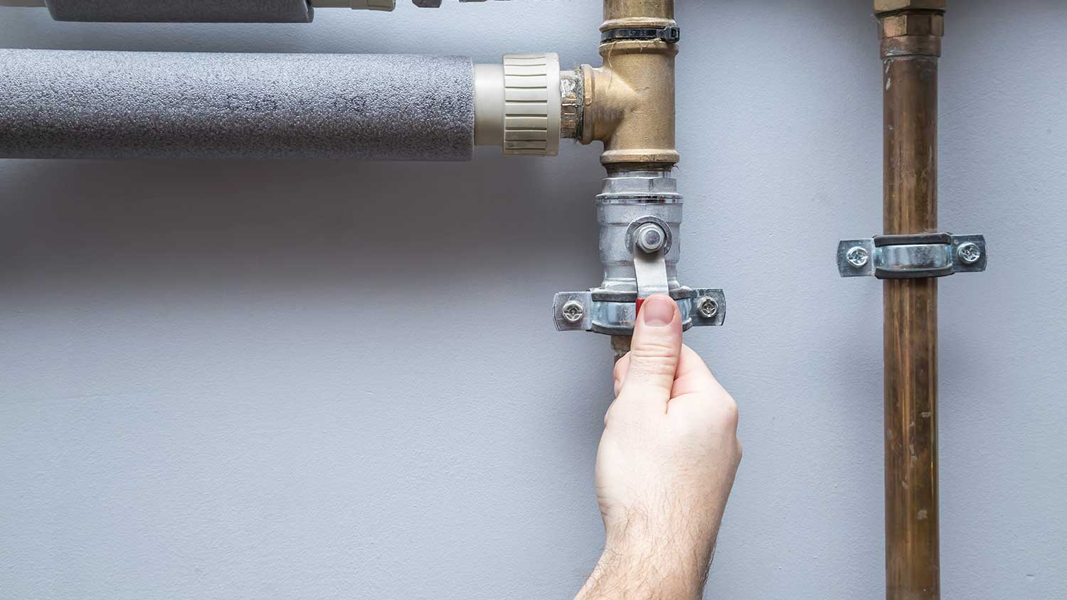Plumber turning of water supply valve in the basement