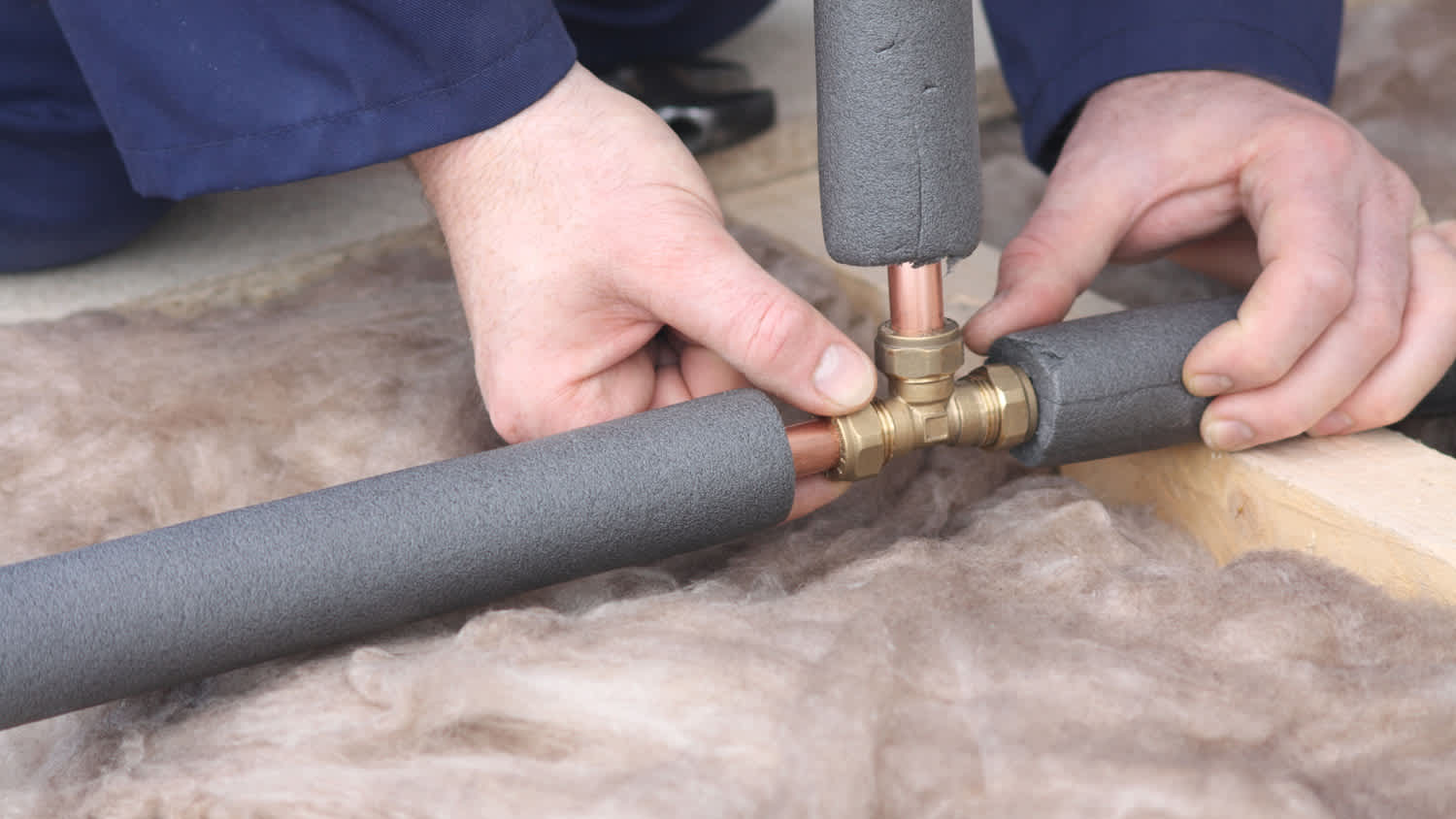 Plumber connecting copper water pipes with foam covering.
