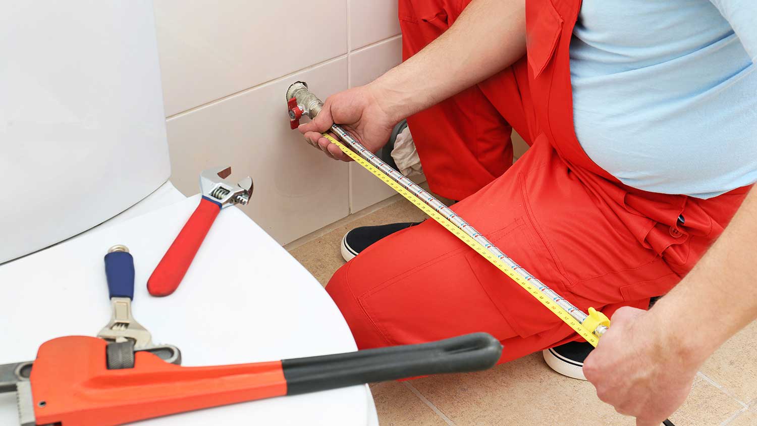 Plumber measuring supply line for the new toilet