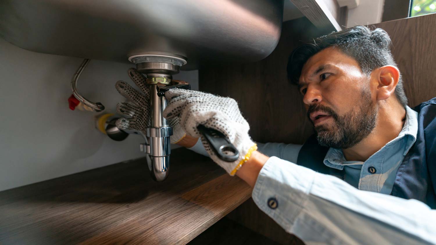 A plumber connecting a p trap to a kitchen sink drain
