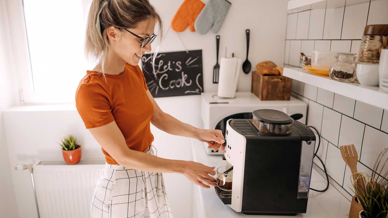 Young woman using coffee machine at home