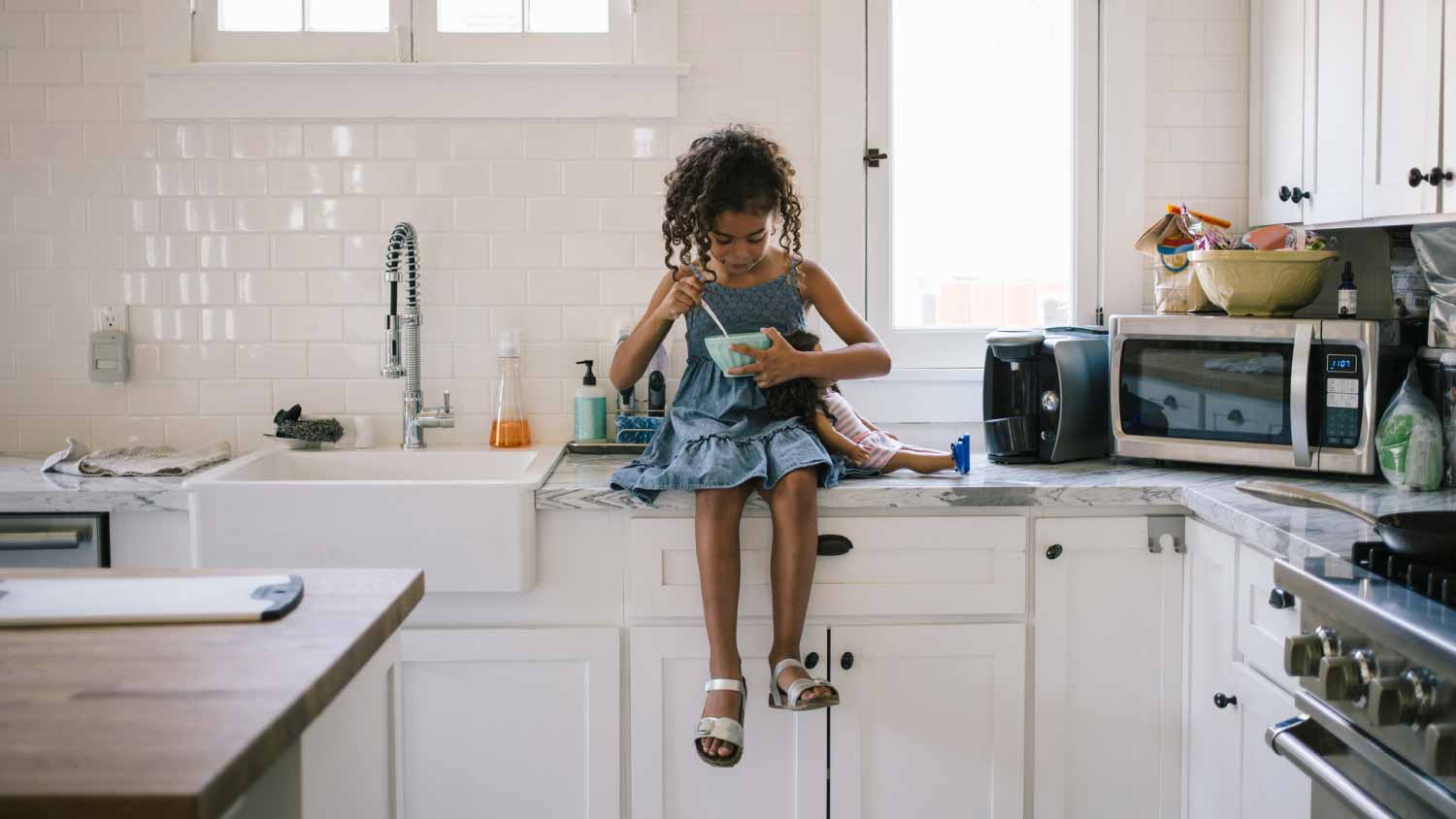 Girl having breakfast while sitting on kitchen