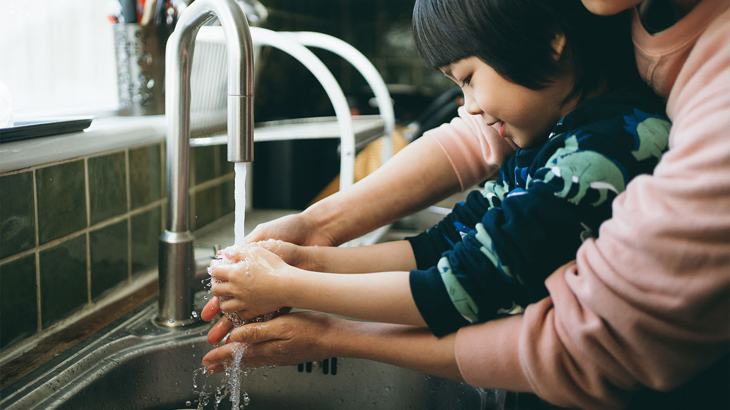 Mother and child washing hands in kitchen