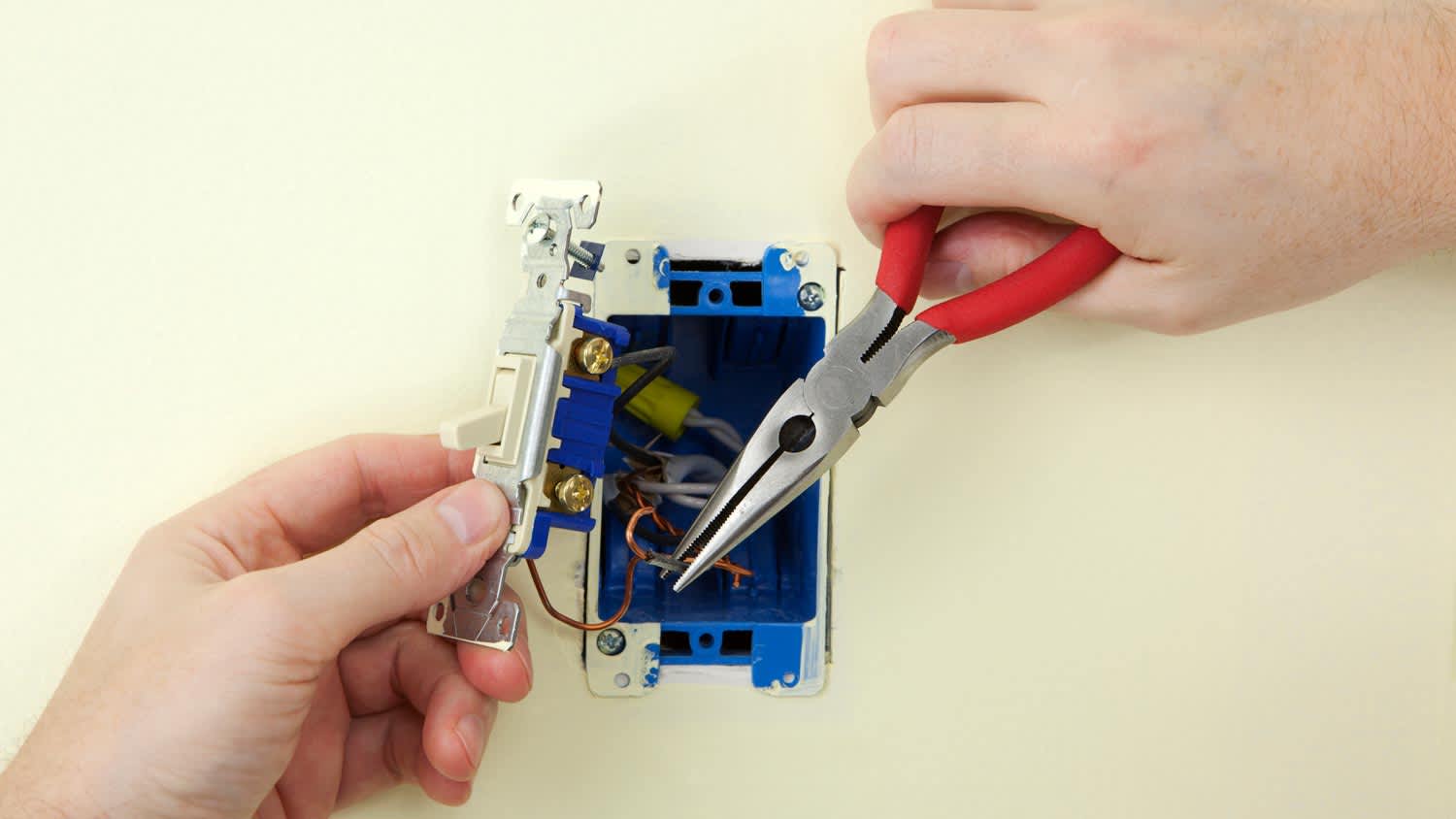 A person wiring a light switch