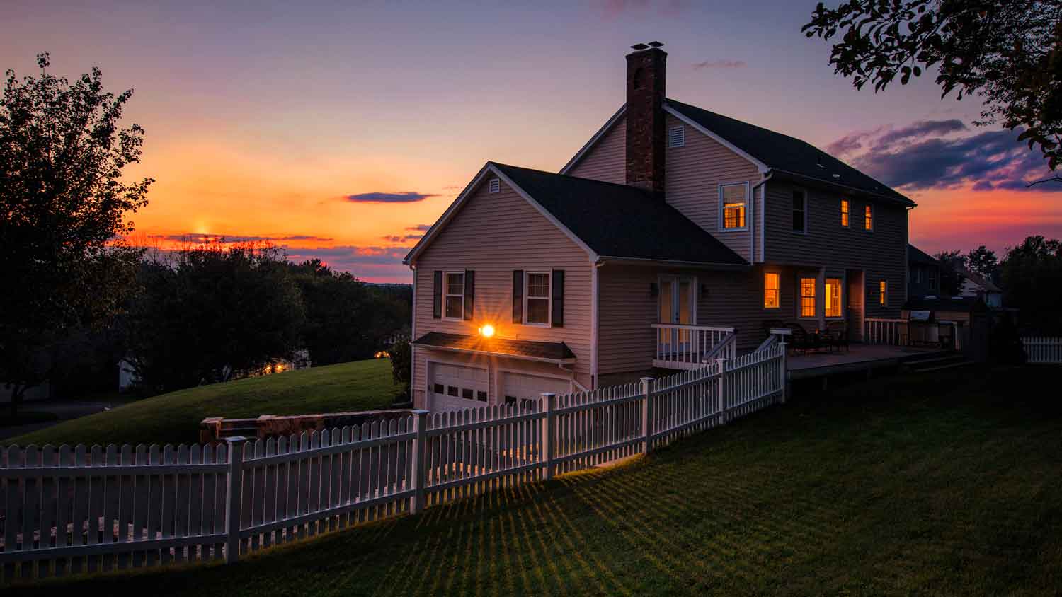 A house at dusk with a floodlight illuminating the big yard